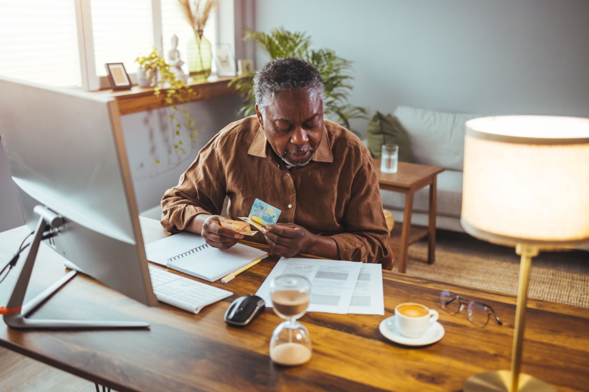 An older gentleman sitting at his home desk browsing the internet and his paperwork to see how to change his Medicare plan