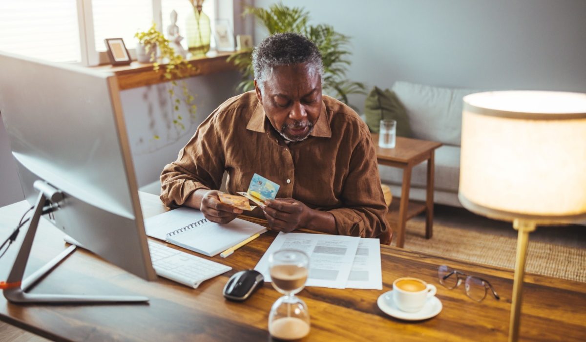 An older gentleman sitting at his home desk browsing the internet and his paperwork to see how to change his Medicare plan